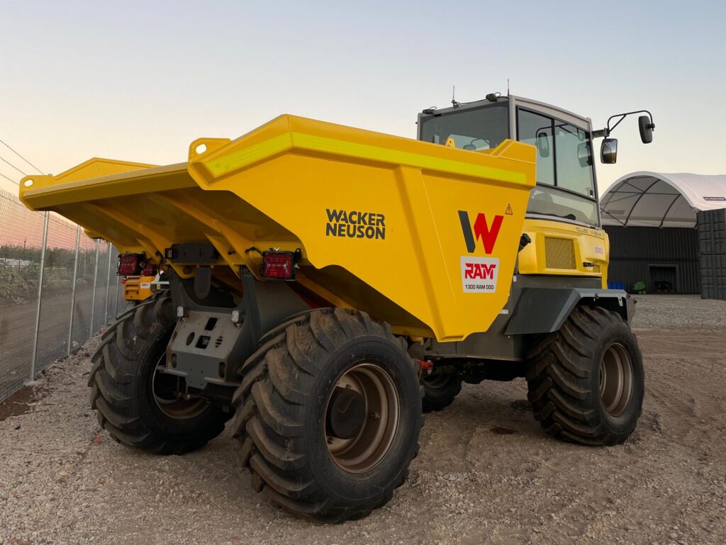 Wacker NEuson Dumper Truck that is tilted on a 45° angle on the dirt during sunrise